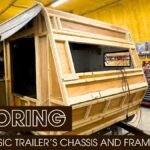 A camper trailer's wooden frame under renovation in a shop.