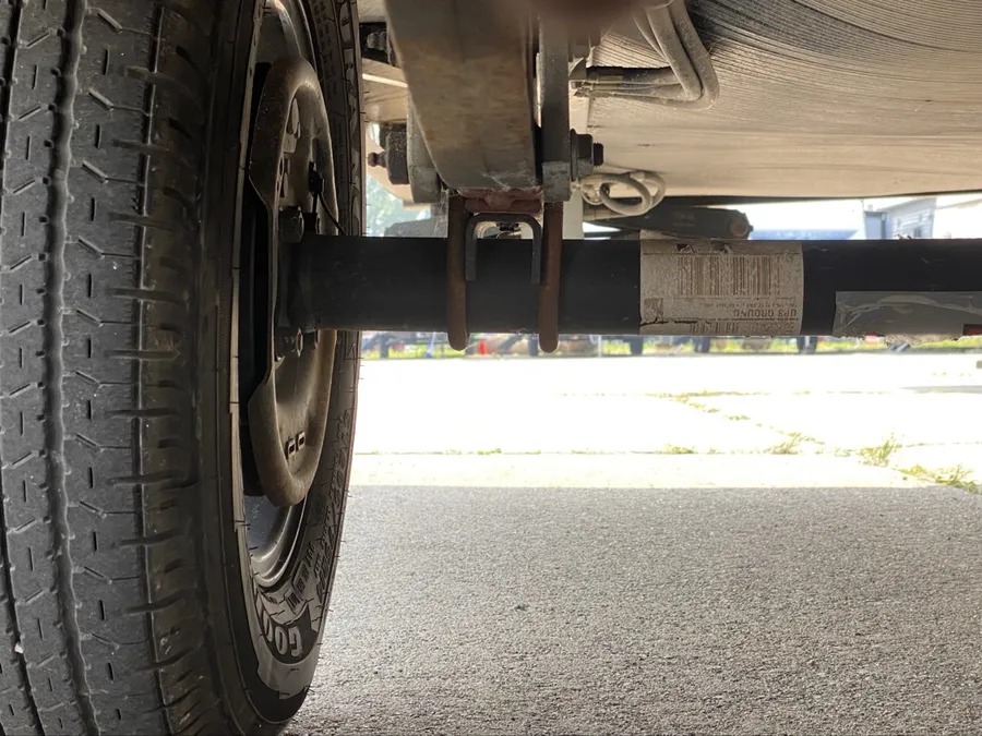 Under-trailer axle, leaf spring and U-bolt close-up with tire — axle and suspension work at Nagel Trailer Repair in Merrill, Michigan