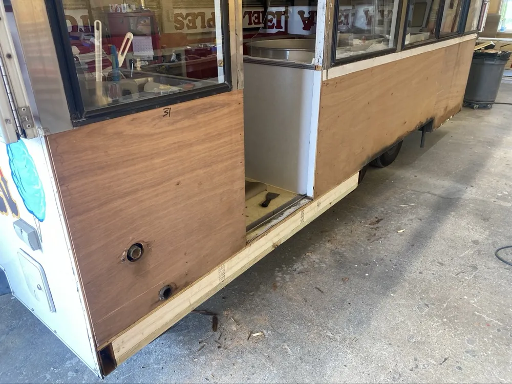 Concession trailer mid-rebuild in the shop at Nagel Trailer Repair in Merrill, Michigan, bare plywood panels exposed