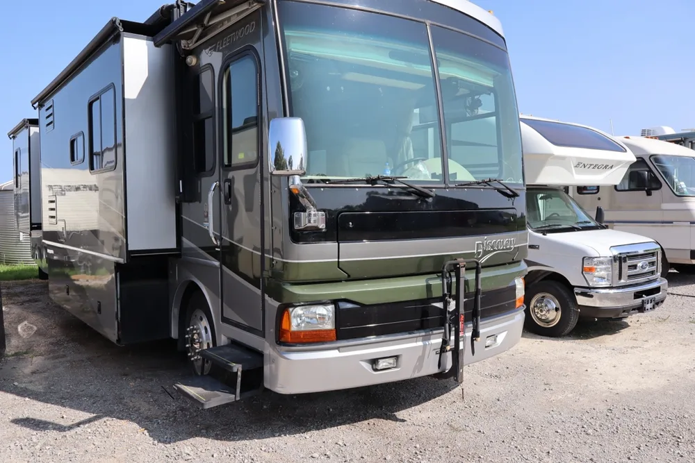 Green and gray Fleetwood Discovery Class A motorhome with its slide out and steps down at the Nagel Trailer Repair yard
