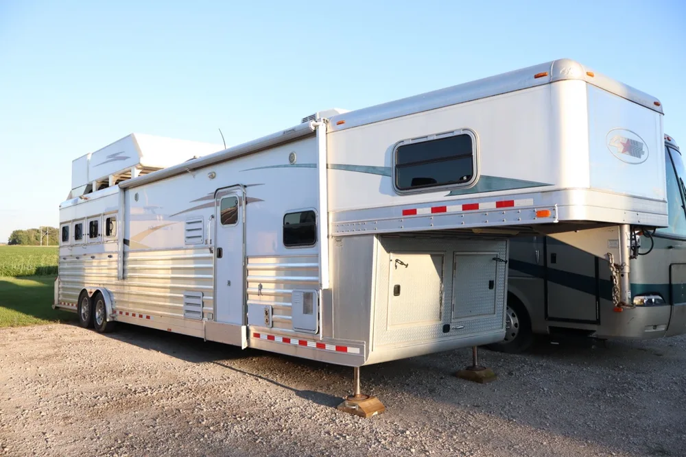 Big aluminum 4-Star gooseneck horse trailer with living quarters parked beside a Class A motorhome at Nagel Trailer Repair in Merrill, Michigan