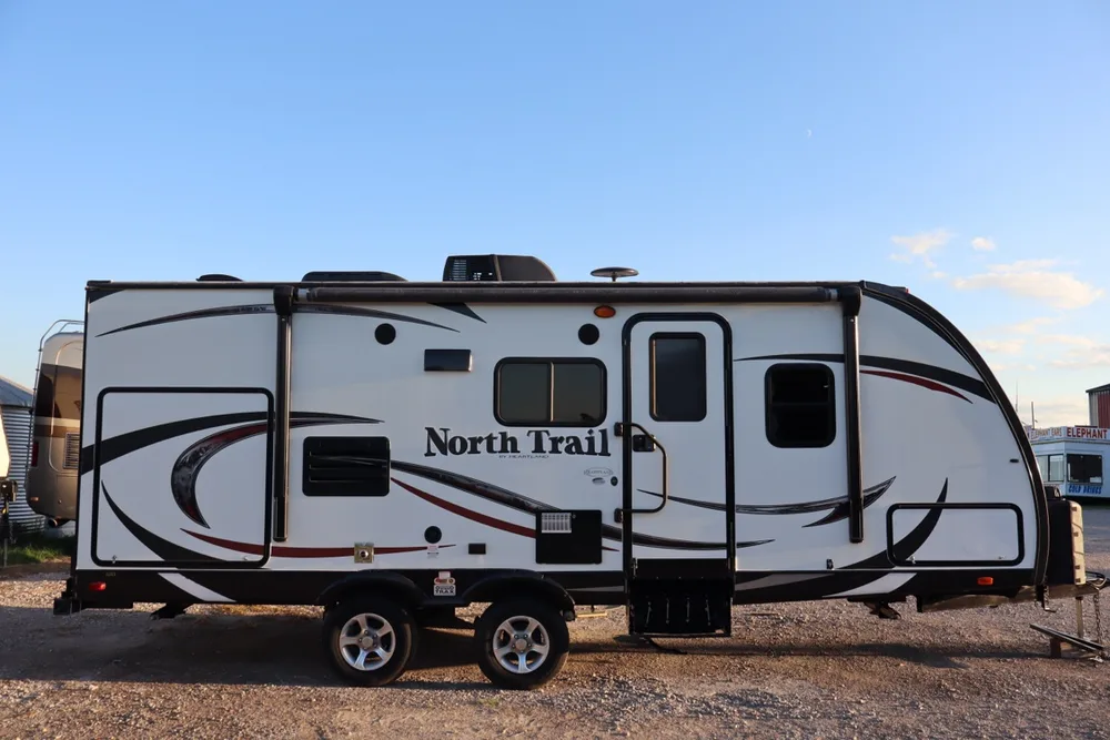 Clean side profile of a modern North Trail by Heartland travel trailer at the Nagel Trailer Repair yard