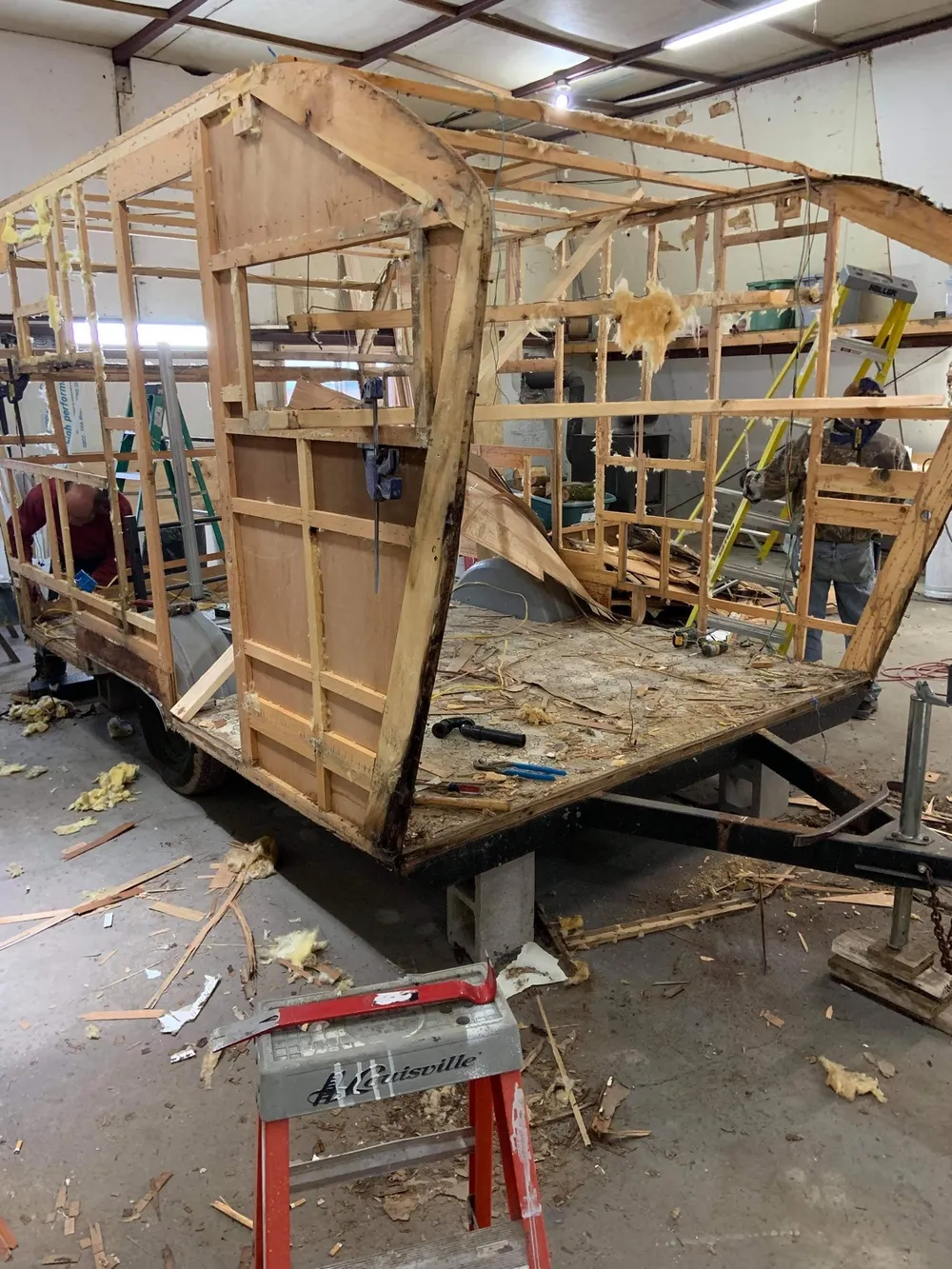 Stage 1 of a vintage camper rebuild at Nagel Trailer Repair in Merrill, Michigan — the camper stripped to its bare wood frame and floor deck