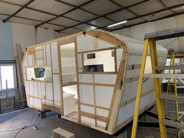 Stage 2 of the rebuild — the rebuilt frame fitted with foam insulation, new cabinetry visible inside