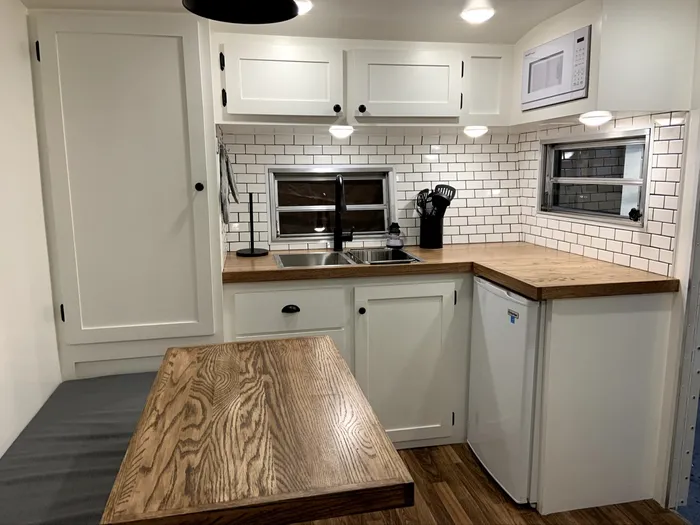 Stage 4 of the rebuild — the finished kitchen: white shaker cabinets, subway tile, butcher-block counters