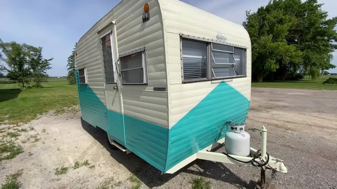 Restored cream and turquoise vintage canned-ham camper in the sun at Nagel Trailer Repair in Merrill, Michigan