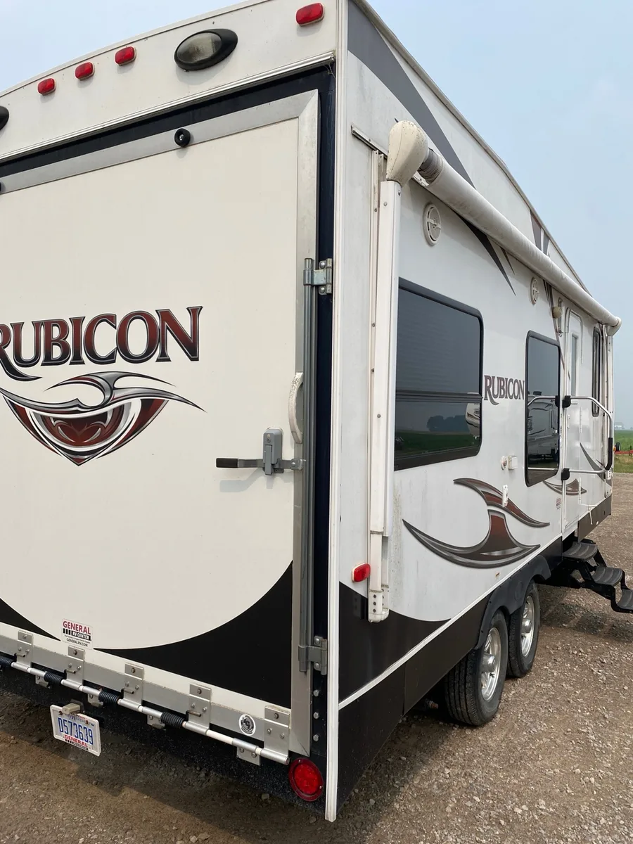 Dutchmen Rubicon toy hauler, rear three-quarter view with ramp door and bold graphics at Nagel Trailer Repair in Merrill, Michigan