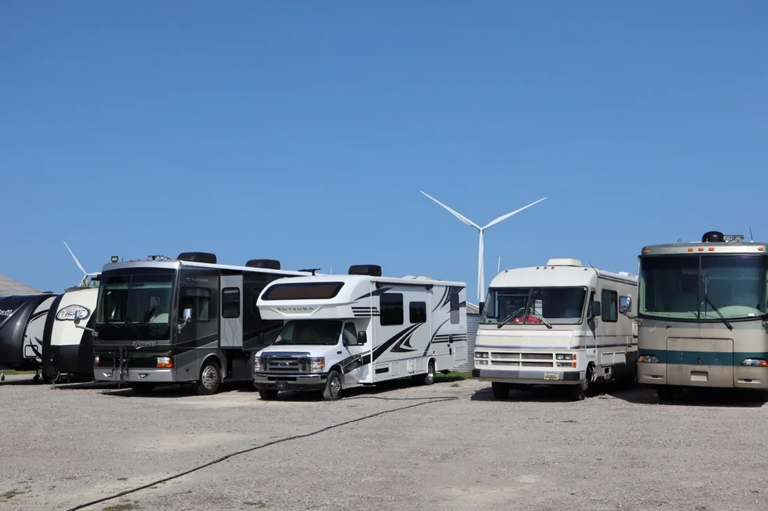 Four motorhomes lined up on the gravel yard at Nagel Trailer Repair in Merrill, Michigan, under a big blue sky